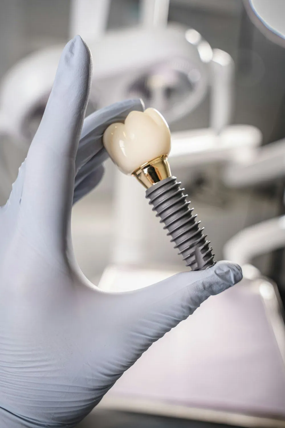 Mano con guante sujetando un implante dental con su corona