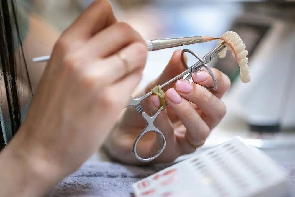Técnico trabajando una prótesis dental con pinzas