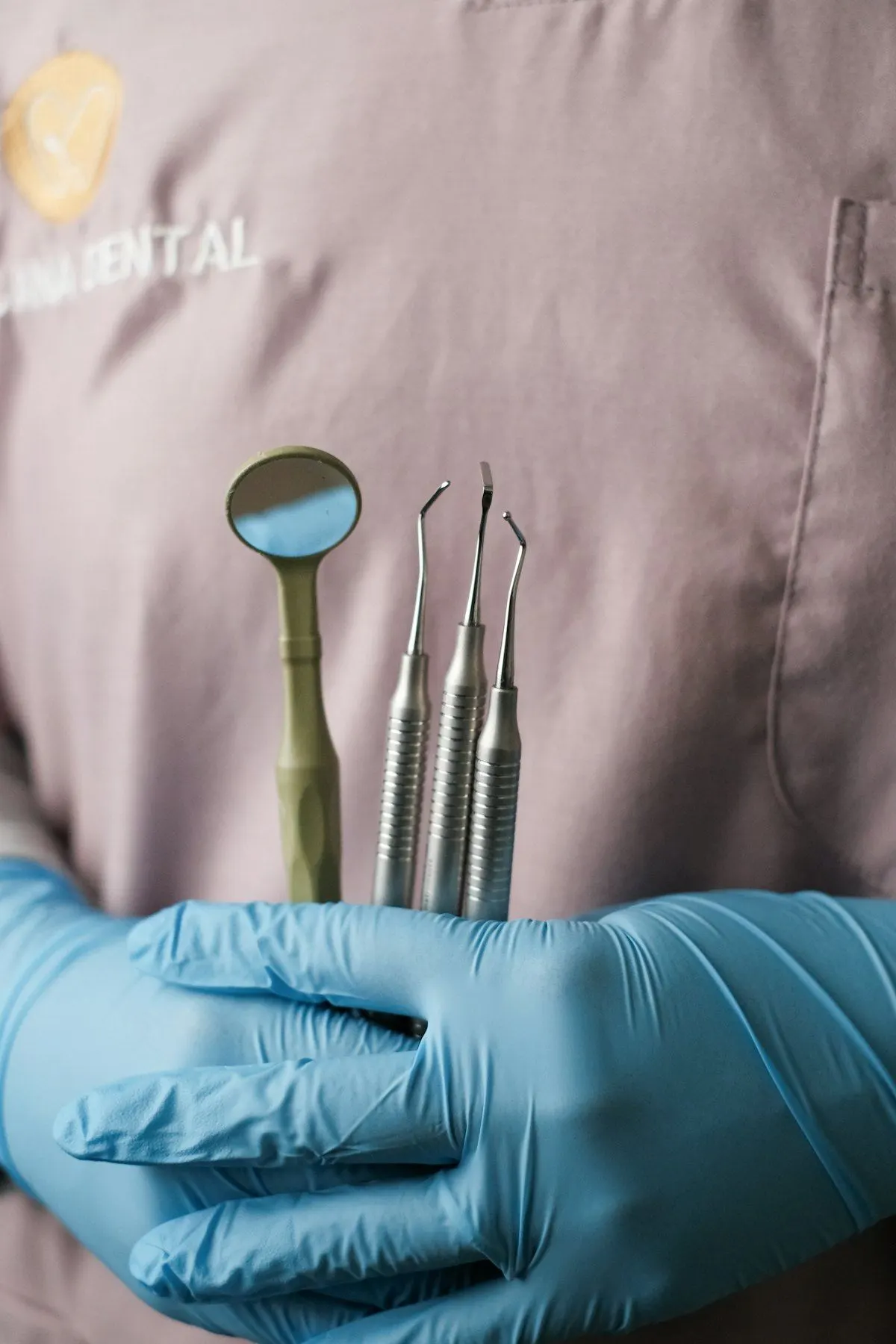 Profesional dental con guantes sujetando instrumental de exploración